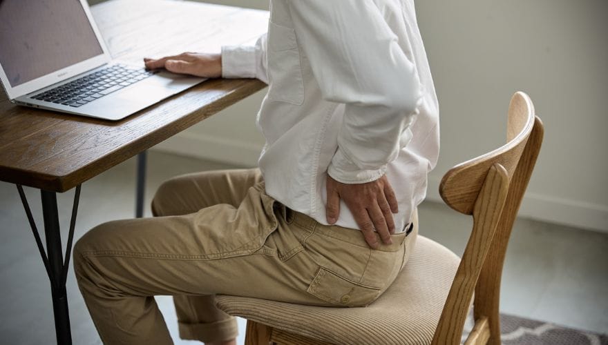 a man with back ache sitting on a chair