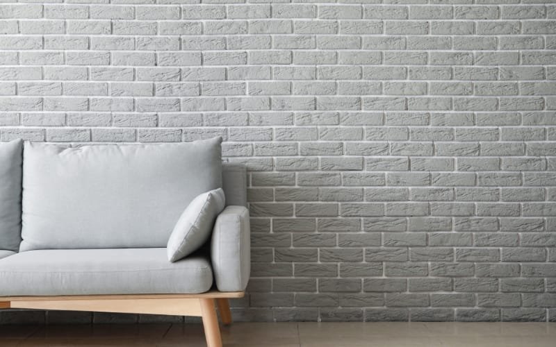 White modern sofa by a brick wall, highlighting sofa placement for minimalist interiors