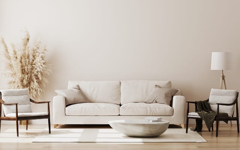 Minimalist cream sofa centered with chairs and round coffee table, showcasing an open living room layout