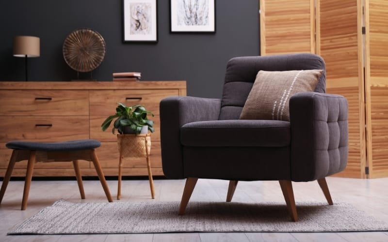 Modern dark gray armchair with wooden side table and plants, perfect for a reading corner