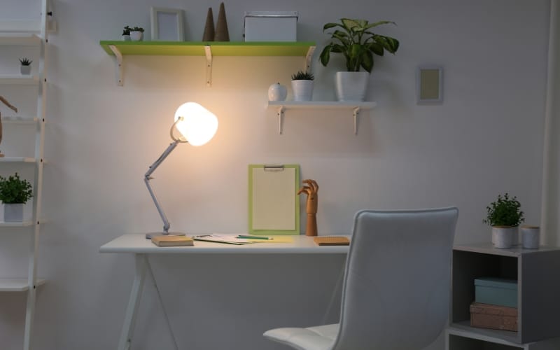 Bright desk setup lighting with a white adjustable lamp in a plant-filled office