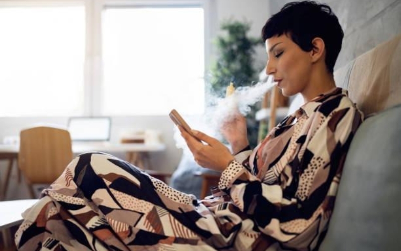 Woman smoking on sofa, with other furniture in background